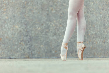 Nahaufnahme der Beine einer Balletttänzerin, die auf den Zehenspitzen steht und Spitzenschuhe trägt. Balletttänzerin übt Tanzschritte. - JLPSF01220