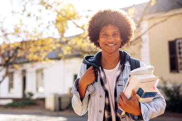 Männlicher College-Student mit vielen Büchern auf dem College-Campus. Gut aussehender junger Mann mit Rucksack auf der Straße. - JLPSF01224