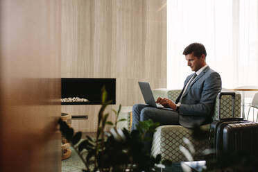 Geschäftsmann sitzt in der Wartehalle des Flughafens und arbeitet am Laptop. Männliche Führungskraft in der Business-Lounge des Flughafens wartet auf den Flug. - JLPSF01237