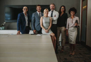 Porträt eines freundlichen multiethnischen Teams von Geschäftsleuten im Sitzungssaal. Ein Team von Geschäftsleuten schaut in die Kamera und lächelt im Konferenzraum. - JLPSF01249