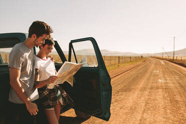 Ein Paar schaut auf eine Karte, um auf einer Schlammpiste zu navigieren. Ein Mann und eine Frau benutzen eine Karte, um durch die Landschaft zu navigieren. - JLPSF01285