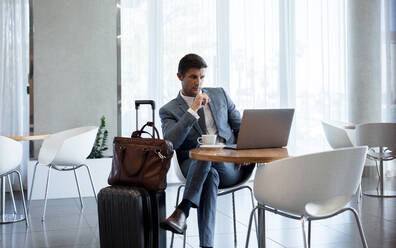 Geschäftsmann sitzt im Flughafen Business Lounge und Blick auf Laptop auf dem Tisch. Business-Mann sitzt am Flughafen Lounge mit Laptop. - JLPSF01321