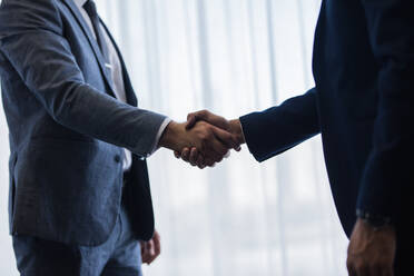 Close up of two businessmen handshaking after good deal. Business people shaking hands and finishing up a meeting in office. - JLPSF01349