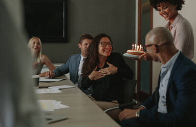 Büroangestellte feiern den Geburtstag einer fröhlichen Kollegin mit einer Torte im Büro. Überraschungs-Geburtstagsfeier einer Mitarbeiterin während einer Personalversammlung. - JLPSF01365