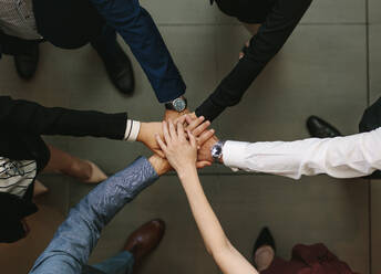 Overhead view of business people hands stacked together. Business team showing unity. - JLPSF01378