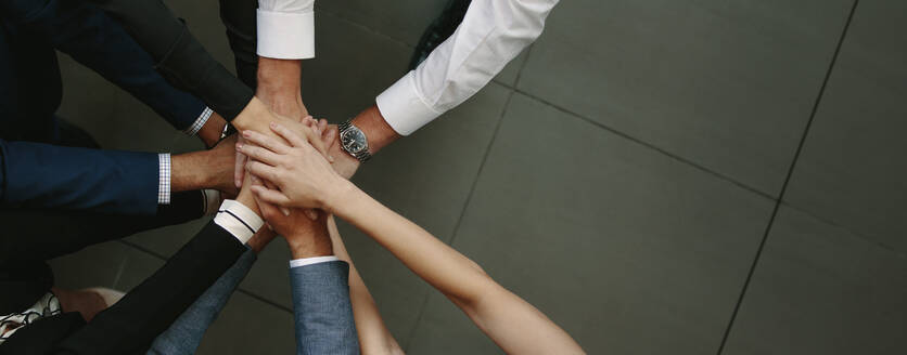 Overhead-Ansicht von Business-Team setzen Hände zusammen im Büro. Büroangestellte machen einen Stapel von Händen mit Kopie Raum. - JLPSF01380