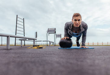 Junge und fitte Sportlerin macht Liegestütze im Freien Fitnessstudio. Fitness Frau macht Liegestütze mit Übungsball. - JLPSF01432