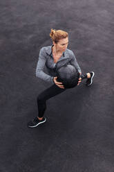 Fit and strong female working out with a medicine ball. Woman doing crossfit workout outdoors. - JLPSF01437