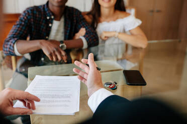 Realtor explaining details of lease agreement to couple. Realtor in discussion with new property owners in an apartment. - JLPSF01456