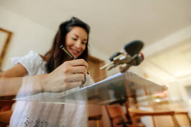 Low angle show of woman buyer reviewing the property documents before signing. Focus on female hand holding pen while signing a contract of new house. - JLPSF01458