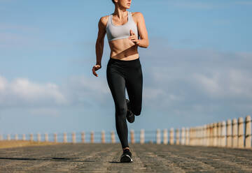 Läuferin beim morgendlichen Training. Junge Frau beim Laufen an der Strandpromenade. - JLPSF01466