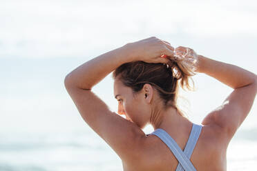 Rear view of fit young woman with muscular body. Fitness female standing outdoors. - JLPSF01477