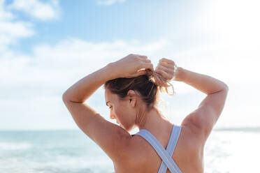 Side view of a smiling athletic woman looking at her biceps during