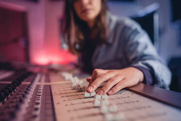 Frauenhände beim Abmischen von Audio in einem Aufnahmestudio. Weibliche Hände arbeiten an einem Musikmischpult. Musikproduktionstechnologie. - JLPSF01484