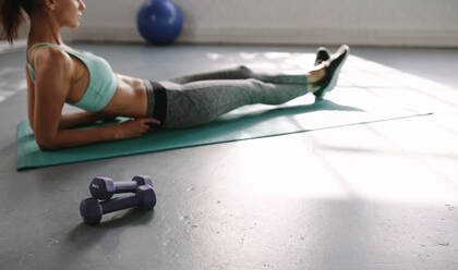 Fitness Frau liegend auf Übungsmatte nach dem Training mit Hanteln vor. Taking Rest im Fitnessstudio nach dem Training. - JLPSF01485