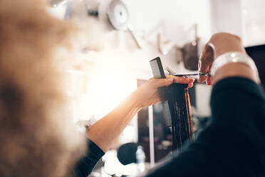 Friseurin, die eine gekämmte Haarsträhne zwischen den Fingern hält. Friseurin, die Haare in einer Ebene schneidet. - JLPSF01488