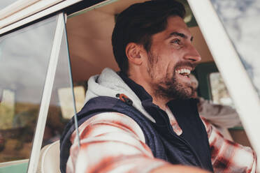 Man driving a van and smiling. Close up of happy caucasian man enjoying on a road trip. - JLPSF01490