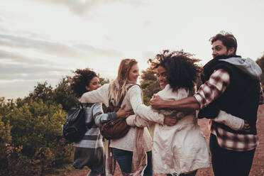 Freunde beim Wandern in der Natur. Eine Gruppe von Männern und Frauen, die zusammen in der Natur spazieren gehen. Glückliche junge Leute, die sich umdrehen und in die Kamera schauen. - JLPSF01540