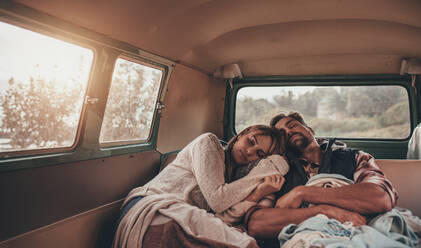 Freunde schlafen zusammen im Van auf einer Autoreise. Mann und Frau schlafen auf dem Rücksitz des Autos. - JLPSF01546