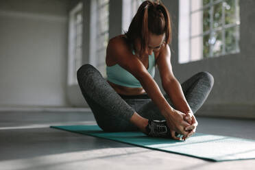 Junge Frau, die im Fitnessstudio trainiert, macht eine Yoga-Übung in Schmetterlingsstellung. - JLPSF01566