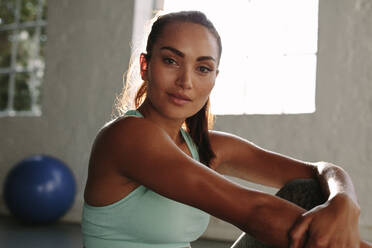 Porträt einer fitten jungen Frau, die sich nach dem Training im Fitnessstudio entspannt. Gesunde Frau, die nach dem Training im Fitnessstudio eine Pause macht. - JLPSF01569