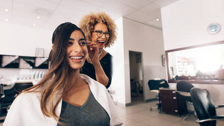 Female hair dresser working on styling a woman 's hair. Hairdresser in a happy mood while working on a woman's hair style. - JLPSF01586