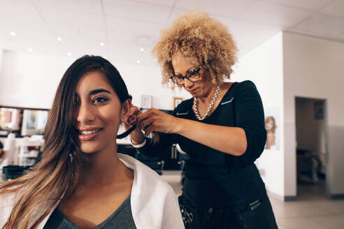 Friseurin bei der Arbeit im Salon. Junge Frau lässt sich im Salon eine modische Frisur machen. - JLPSF01587