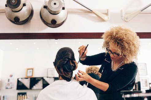Professionelle Friseurin stylt die Haare eines Kunden im Salon. Weibliche Friseurin stellt Haare in modischem Design. - JLPSF01591