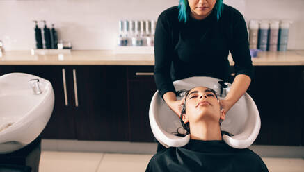 Friseur, der einer Kundin im Salon die Haare wäscht. Frau, die in einem Schönheitssalon eine Haarpflegebehandlung erhält. - JLPSF01596