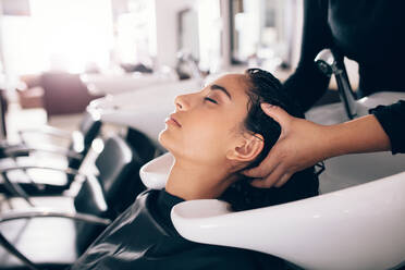 Eine Friseurin spült die Haare einer Kundin, die eine Wellness-Behandlung im Salon erhält. - JLPSF01603