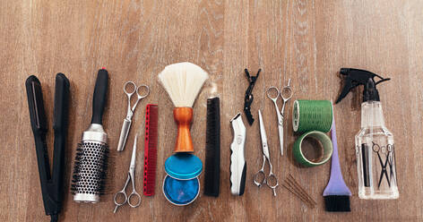 Professional hairdresser tools on wooden surface. Top view of hairdresser accessories arranged in line. - JLPSF01608