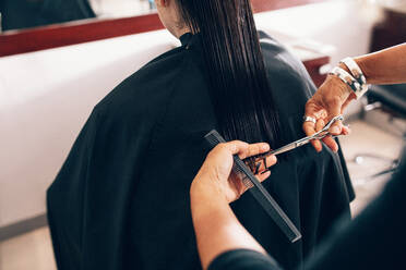 Hair stylist cutting the hair to a straight level. Hairdresser using comb and scissors for a hair cut. - JLPSF01615