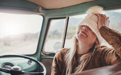Woman on a road trip. Young female wearing warm clothing sitting in van making funny face. - JLPSF01629
