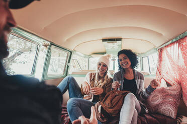 Friends on roadtrip smiling and laughing inside van. Young people travelling together in a van and having fun. - JLPSF01638