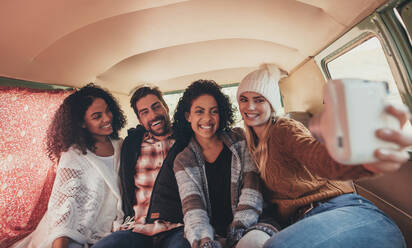 Freunde sitzen zusammen im Van und machen ein Selfie auf einer Autoreise. Frau macht Selfie mit Freunden mit Digitalkamera. - JLPSF01643