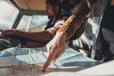 Nahaufnahme einer Frau, die auf die Karte zeigt, während ein Mann im Hintergrund einen Van fährt. - JLPSF01647