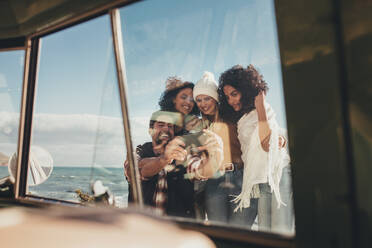 Gruppe von Freunden machen Selbstporträt im Freien auf Road Trip. Schuss aus dem Van von Mann und Frauen, die Selfie im Urlaub. - JLPSF01656