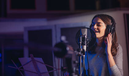 Female playback singer recording album in the professional studio. Woman singing a song in music recording studio. - JLPSF01668