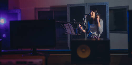 Woman recording a song in music studio. Female playback singer recording her album. - JLPSF01669