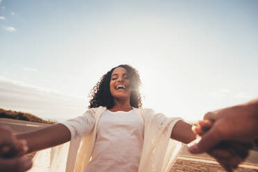 POV shot of smiling african woman spinning with her boyfriend. Laughing female holding hands of her boyfriend and having fun. - JLPSF01685