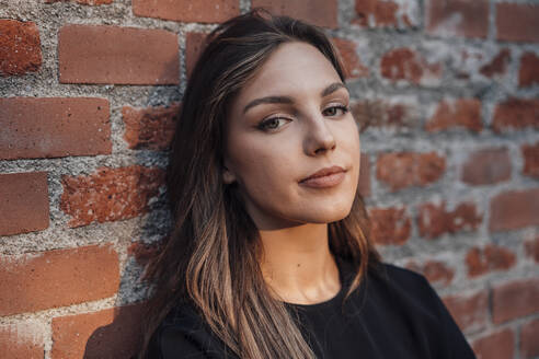 Young woman in front of brick wall - JOSEF13476