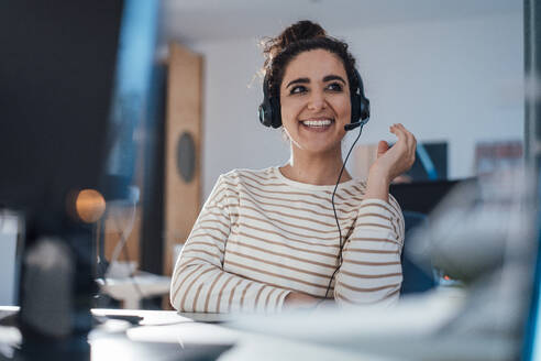 Lächelnde Geschäftsfrau, die über ein Headset im Büro spricht - JOSEF13554