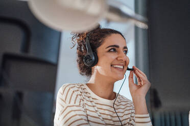 Kundendienstmitarbeiter, der im Büro über ein Headset spricht - JOSEF13556