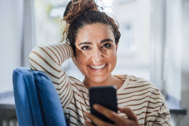 Happy woman with smart phone at home - JOSEF13583
