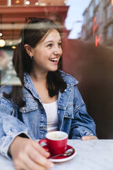 Contemplative woman wearing denim jacket at cafe - ASGF02902