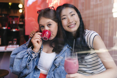 Young lesbian couple enjoying drinks at cafe - ASGF02906