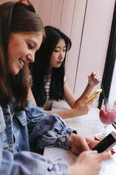Lesbian couple using smart phones at cafe - ASGF02908