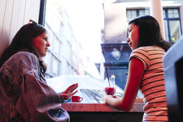 Lesbian friends talking to each other sitting in cafe - ASGF02912