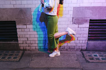 Woman standing on one leg in front of brick wall - ASGF02926