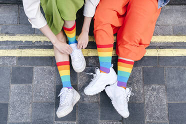 Young lesbian couple wearing multi colored socks at footpath - ASGF02965